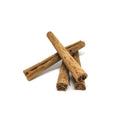 a pile of cinnamon quills on a white background