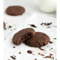 Two Brownie Bites, one half eaten on a white background with crumbs surrounding them and another brownie bite in the background