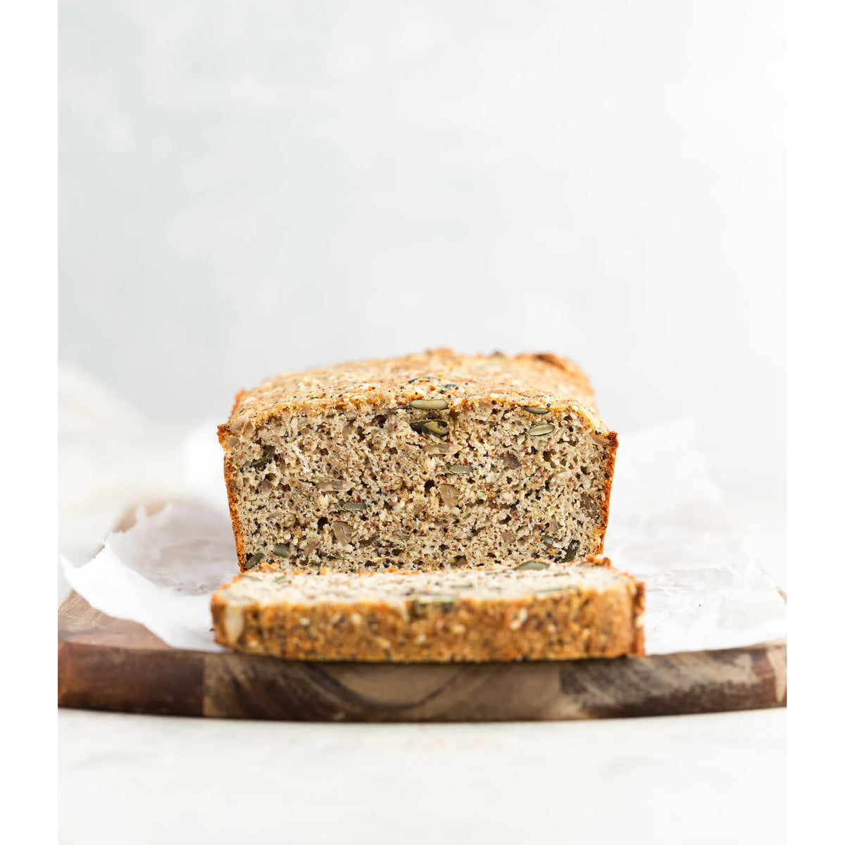 Loaf of bread on a wooden cutting board with a white background