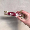 Hand holding a Mac Bar chocolate bar against a plain background